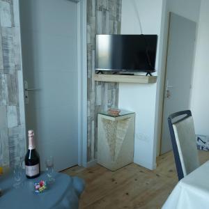 Habitación con mesa, botella de vino y TV. en Charmant appartement proche Carcassonne, en Montgradail
