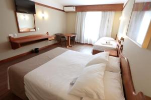 ein Hotelzimmer mit einem großen Bett und einem Schreibtisch in der Unterkunft Tri Hotel in Canela