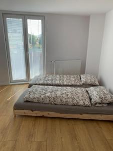 2 bedden in een witte kamer met houten vloeren bij Apartman Tatry in Mlynica