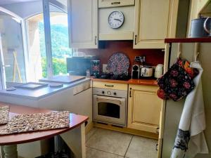 a kitchen with a stove and a clock on the wall at La maison de Ninia in Digne-les-Bains