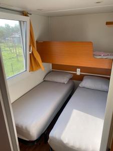 two beds in a small room with a window at Agricamping Zanina 9 in Peschiera del Garda