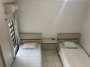 um pequeno quarto com 2 camas e uma secretária em PREMIER HOTEL em Marabá