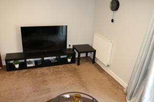 a living room with a flat screen tv and a table at 4 Bed Luxury Home in Broughton by Goshen Properties in Milton Keynes