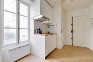 una cocina con armarios blancos y una ventana en INVALIDES - TOUR EIFFEL, en París