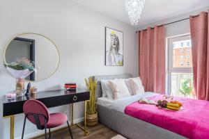 Lumina premium apartments with balcony, parking في لودز: غرفة نوم مع سرير ومكتب مع بطانية وردية