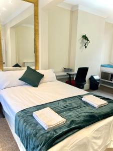 een slaapkamer met een bed met twee handdoeken erop bij Aldgate Holiday Rooms in Londen