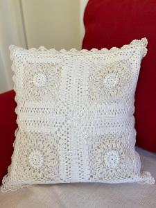 a white crochet pillow sitting on a red chair at Maslina in Orebić