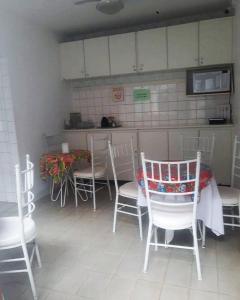 a dining room with white chairs and a table at Hostel Diniz in Vitória