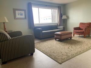 a living room with chairs and a couch and a window at Gold Coast Family Cottages in Oscoda