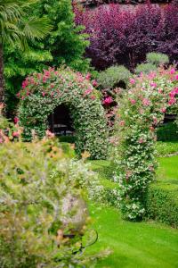 a garden with pink and white flowers and bushes at Real Scampis Hotel in Elbasan