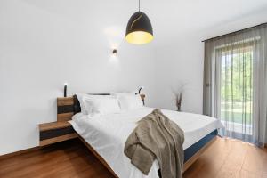 Schlafzimmer mit einem Bett mit weißer Bettwäsche und einem Fenster in der Unterkunft Apartment Mia in Labin