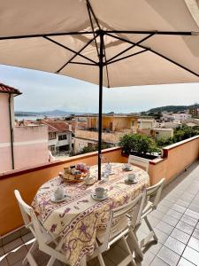 d'une table et de chaises sur un balcon avec un parasol dans l'établissement Appartamento Centrale, con posto auto., à La Maddalena