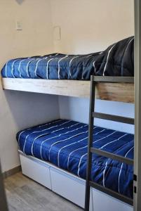 2 Etagenbetten mit blauer Bettwäsche und einer Leiter in der Unterkunft Cabana 7 loma de la cruz in Tafí del Valle