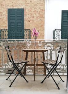 皮斯蒂奇的住宿－Il Vicoletto，阳台上的桌子、两把椅子和花瓶