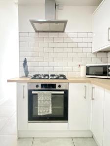 a kitchen with a stove and white cabinets at Town Center Retreat 2 Bed Gem with Free Parking and Garden in Buckinghamshire