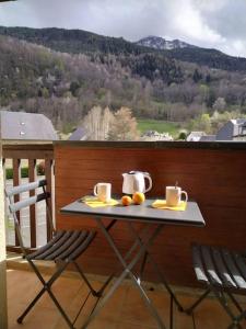 stół z dwoma filiżankami i pomarańczami na balkonie w obiekcie Appartement dans une Résidence Calme (4 Personnes) w mieście Saint-Lary-Soulan