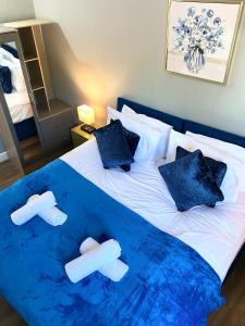 uma cama com um cobertor azul e chinelos em Town Center Retreat 2 Bed Gem with Free Parking and Garden em Buckinghamshire