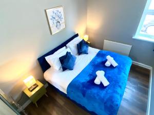 a bedroom with a bed with blue sheets and blue pillows at Town Center Retreat 2 Bed Gem with Free Parking and Garden in Buckinghamshire