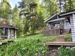 a log cabin in the woods with a porch at Lepikkorinne Raijan Aitta in Mikkeli