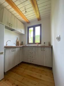 a kitchen with white cabinets and a window at Cabana Gavroche in Moara Ungurului +21 photos