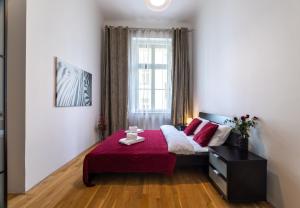プラハにあるLesser Town Apartment Melnicka by easyBNBのベッドルーム1室(赤毛布、窓付)