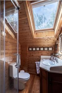 een badkamer met een toilet, een wastafel en een raam bij Prado do Xisto - Chalé de madeira a 7km de Braga in Braga