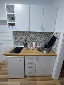uma cozinha com armários brancos e um lavatório em Jaz Apartman em Bajina Bašta