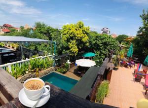 a cup of coffee sitting on a table next to a pool at Antonios Villa Hotel in Siem Reap