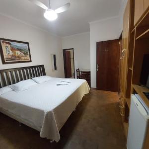 a bedroom with a white bed with a ceiling at HOTEL SOARES CAMARGO in Salesópolis