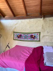 Cama morada en una habitación con pared en Cabaña La Sencillita, en Neptunia