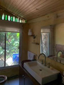 baño con lavabo, espejo y ventana en Cabaña La Sencillita, en Neptunia