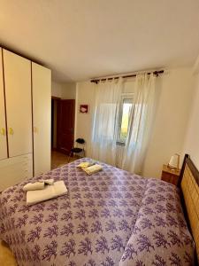 1 dormitorio con 1 cama morada y 2 toallas en Appartamento Centrale, con posto auto. en La Maddalena