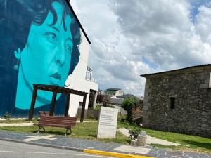 un mural de una mujer en un edificio con un banco en Jabego2 en Sarria