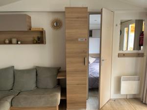 uma sala de estar com um sofá e um quarto em Mobil home climatisé em Lège-Cap-Ferret