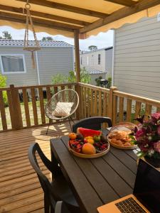 a table with two plates of fruit on a deck at Mobil home climatisé in Lège-Cap-Ferret