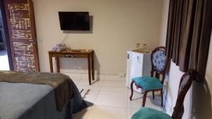 a room with a bed and a chair and a television at Caminho do Sol Pousada in Chapada dos Guimarães