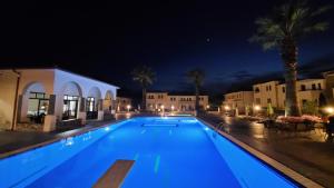 a swimming pool at night with palm trees and buildings at Amari Hotel in Metamorfosi