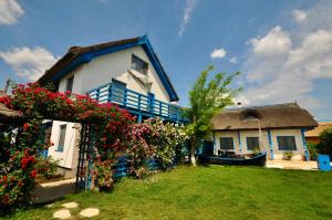 una casa con techo de paja y un patio con flores en Pension Sharaiman, en Dunavăţu de Jos