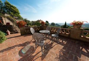 eine Terrasse mit 4 Stühlen und einem Tisch auf einer Backsteinterrasse in der Unterkunft Conca di Sopra Home in Corsanico-Bargecchia
