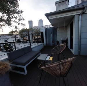 une terrasse avec un canapé, une table et une chaise dans l'établissement Appartement Cosy et Moderne Puteaux Paris La Defense, à Puteaux