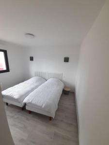 2 camas en una habitación con paredes blancas en maison neuve a 1 km de la plage, en Saint-Germain-sur-Ay