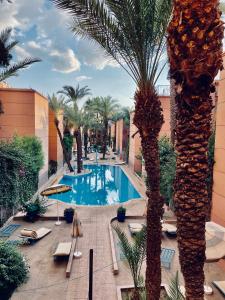 una piscina del complejo con palmeras y tumbonas en Riad Palmeraie en Marrakech
