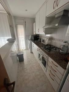 La cuisine est équipée de placards blancs et d'un four avec plaques de cuisson. dans l'établissement Apartamento céntrico en Blanes, à Blanes