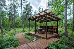 een houten terras met een tuinhuisje in het bos bij SHANTI FOREST HOUSE Guest house with mirror sauna 