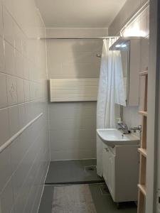 La salle de bains blanche est pourvue d'un lavabo et d'une douche. dans l'établissement PoppaLiving Oy II, à Vaasa