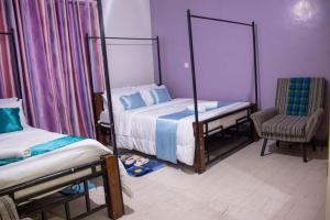 sypialnia z 2 łóżkami pojedynczymi i krzesłem w obiekcie Kwe Decasa w mieście Kisumu