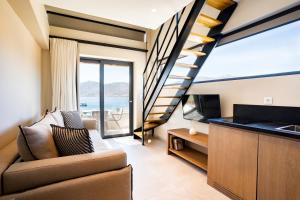 a living room with a staircase and a couch and a television at Elivia Boutique Suites in Almiropótamos