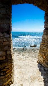 einen Blick auf das Meer durch eine Steinmauer in der Unterkunft Guest House Torci 18 in Novigrad Istria