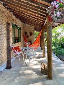 een patio met een tafel en stoelen onder een houten dak bij Casa charmosa em condomínio arborizado in Nova Lima