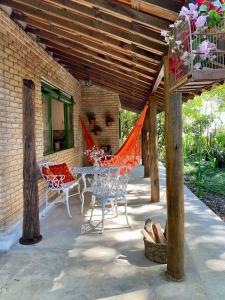 un patio con mesa y sillas bajo un techo de madera en Casa charmosa em condomínio arborizado, en Nova Lima